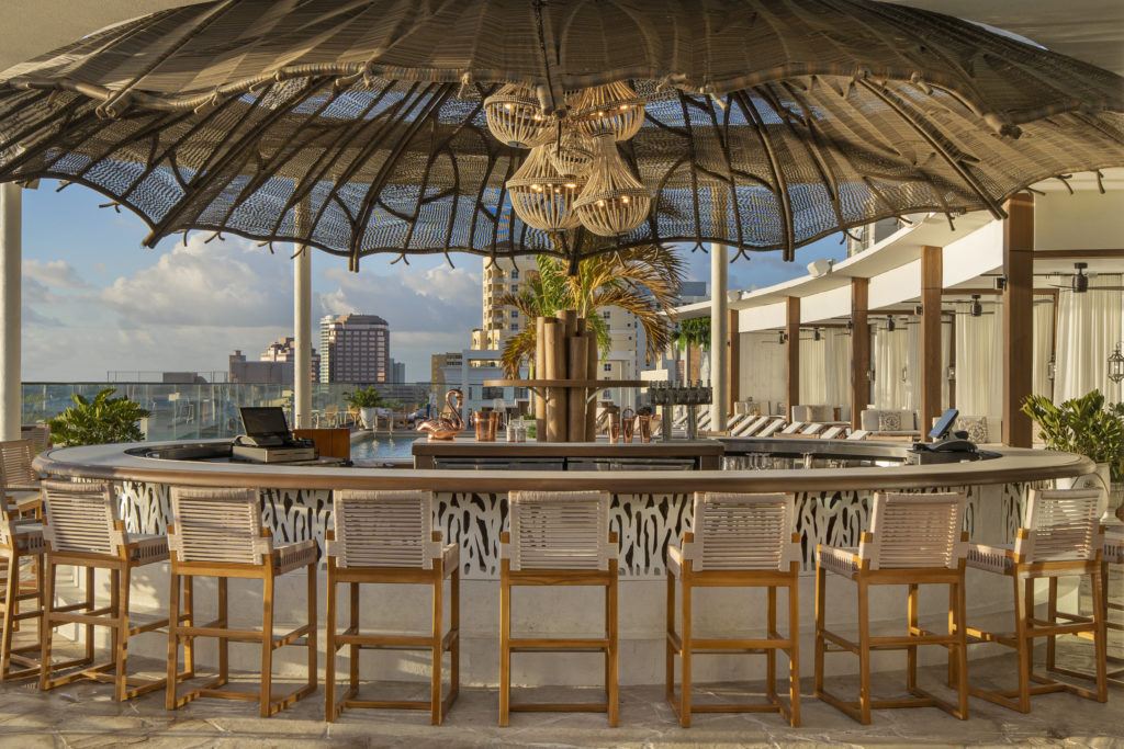 Spruzzo, The Ben's rooftop bar, set with woven chairs and string lights overlooking the marina at sunset.