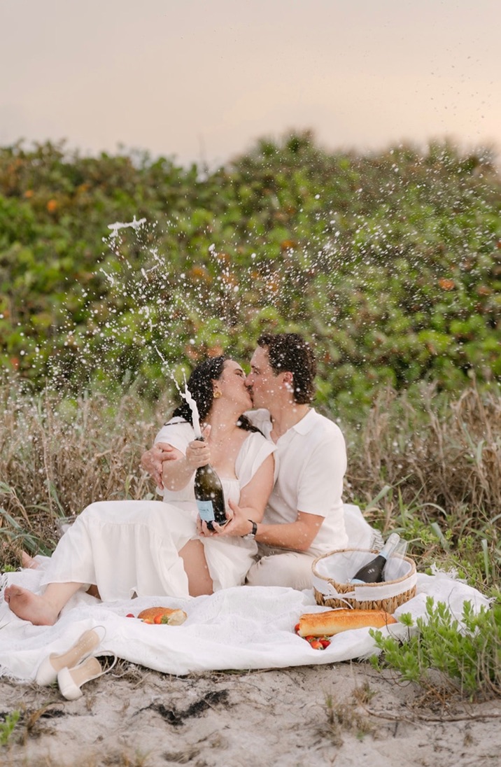 Claudia and Marcus kissing while champagne sprays above them.