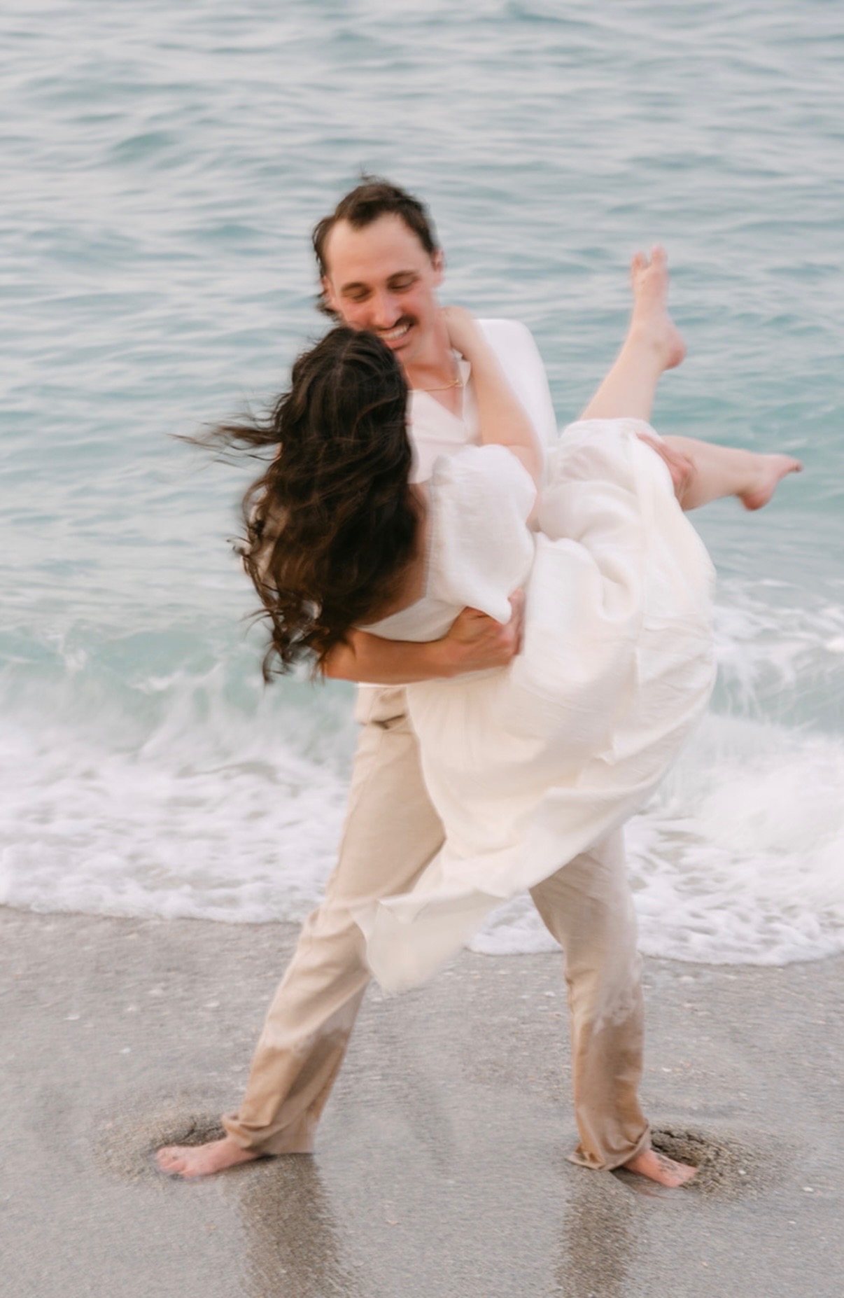 Marcus carrying Claudia at the water's edge.