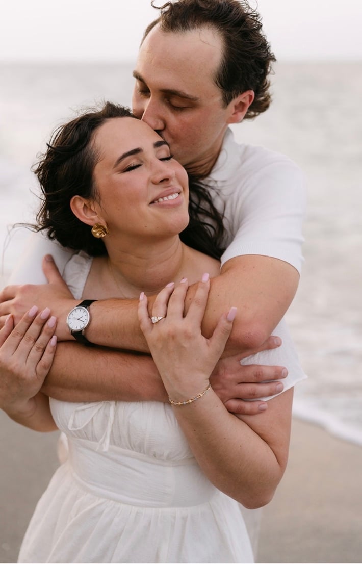 Marcus holding Claudia close on the beach.