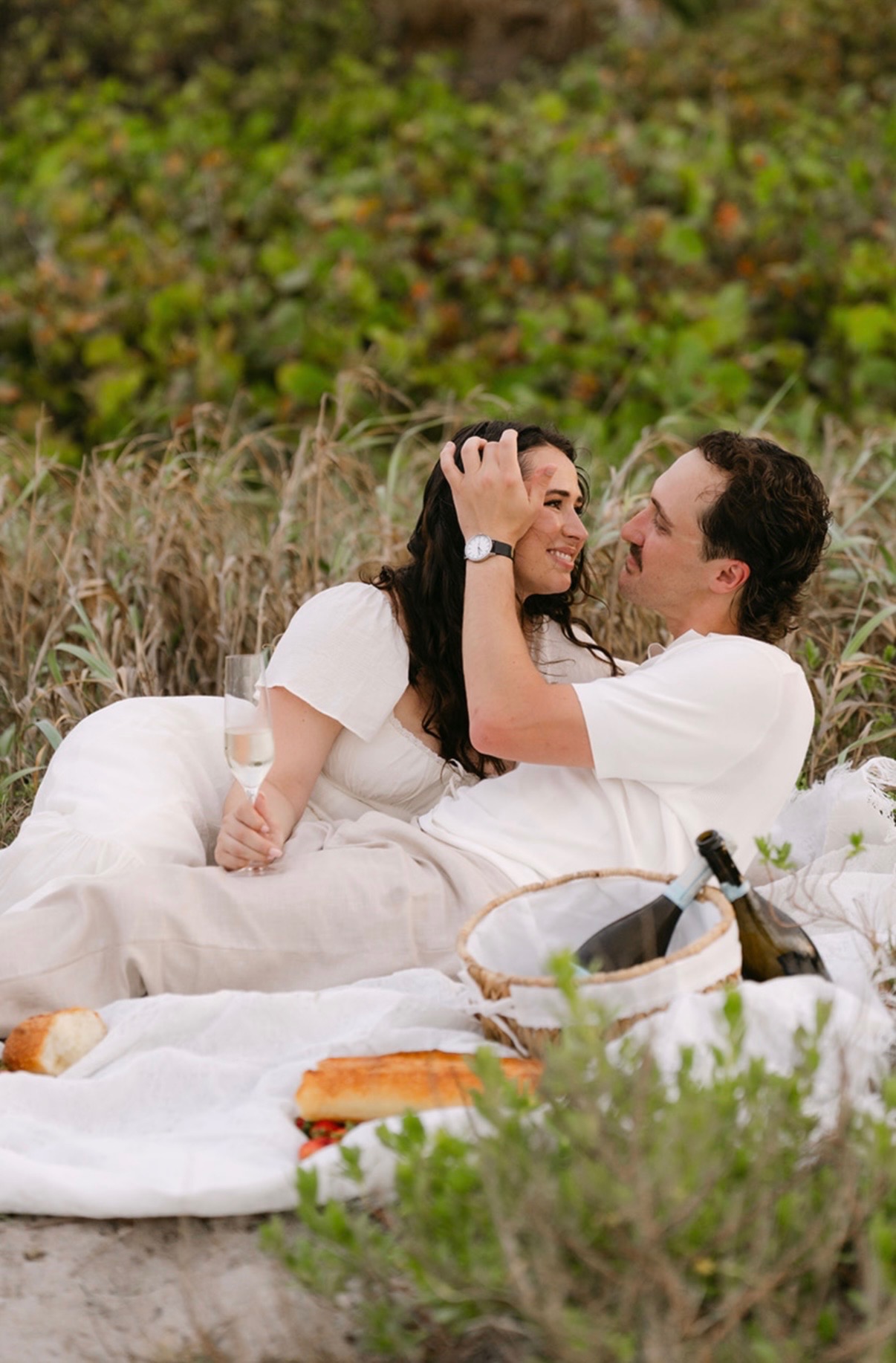 Marcus brushing Claudia's hair back as they lie on a beach blanket.