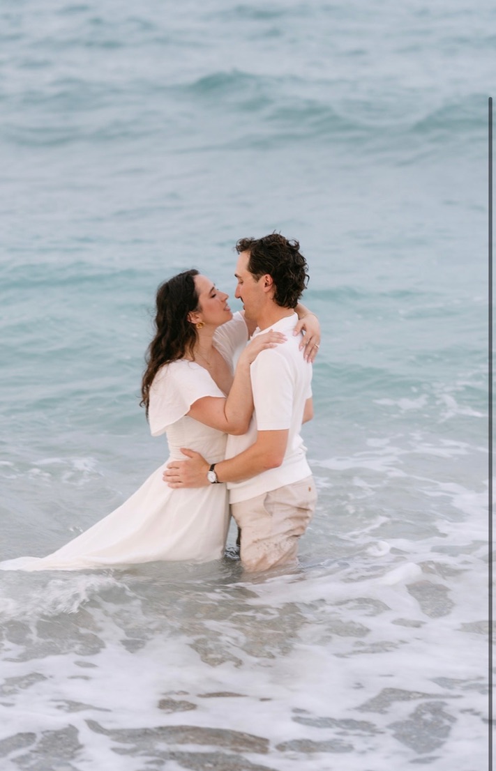 Claudia and Marcus standing together in ocean waves.