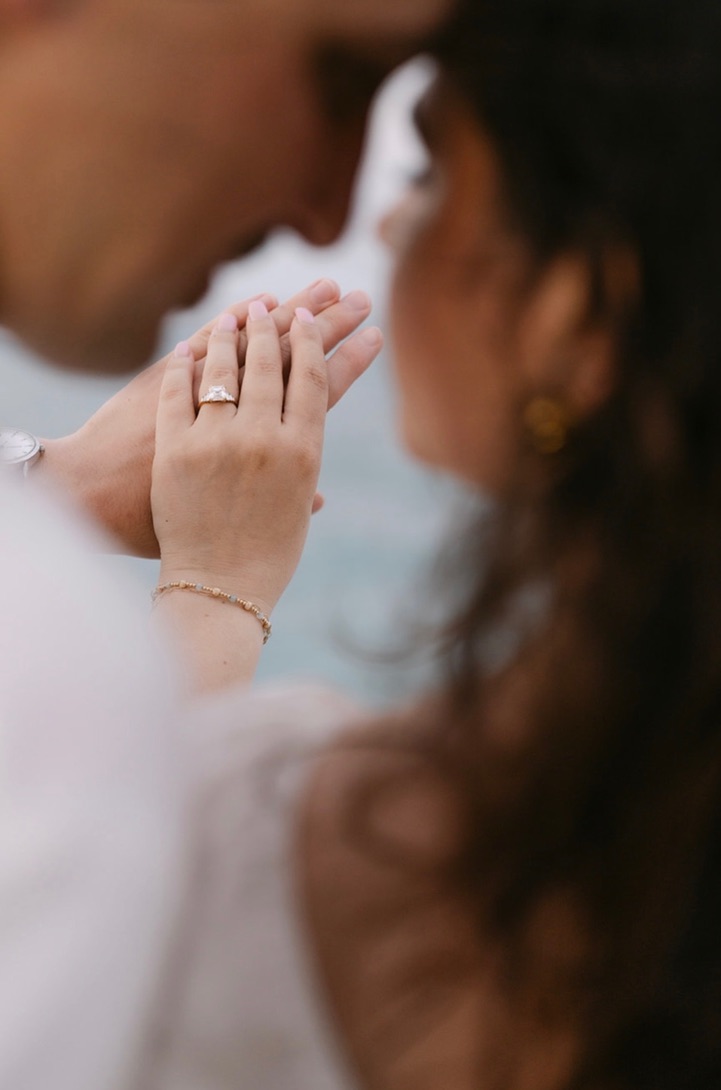 Close-up of Claudia's engagement ring while the couple holds hands.