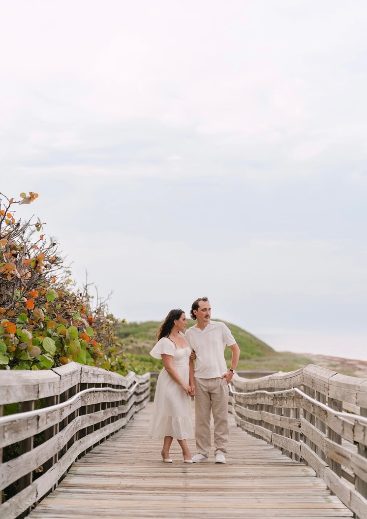 Claudia and Marcus walking together on a beach boardwalk.