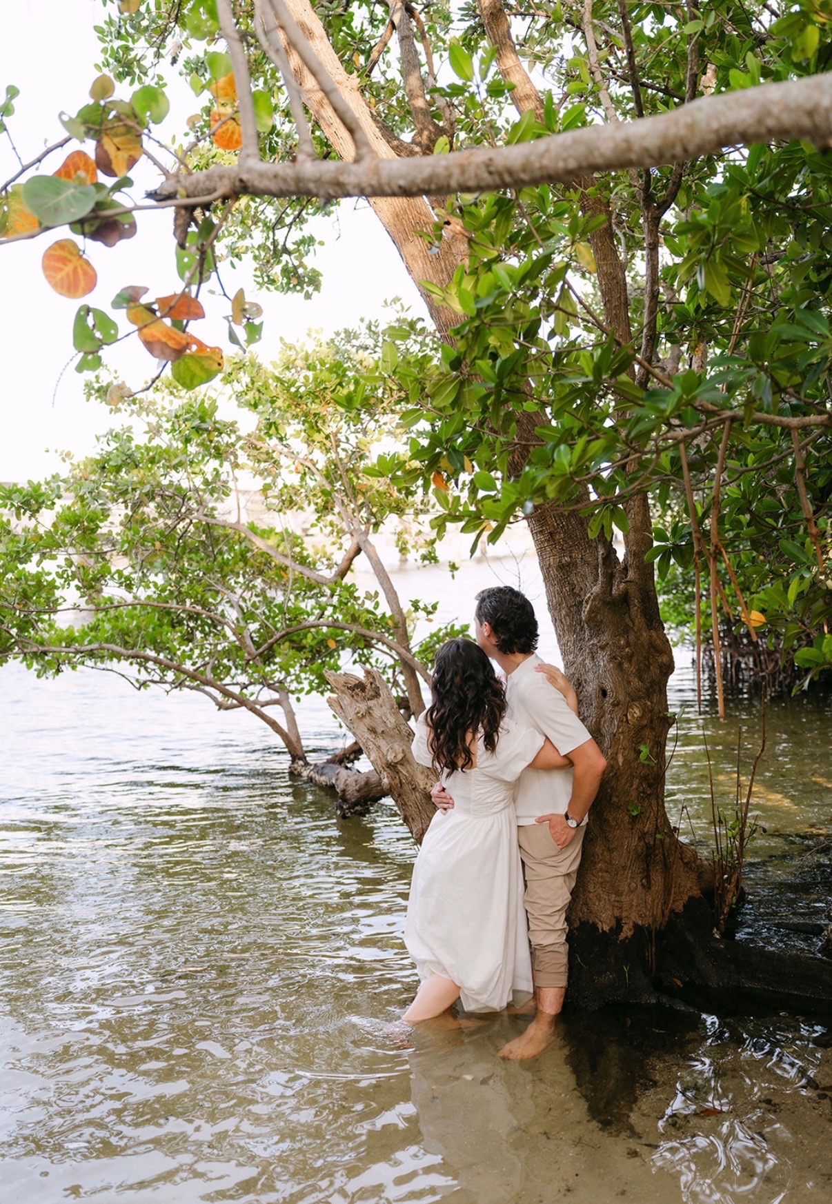Claudia and Marcus looking toward the water under mangrove branches.