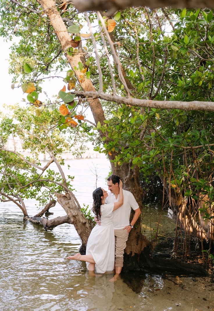 The couple standing beside a mangrove tree in shallow water.