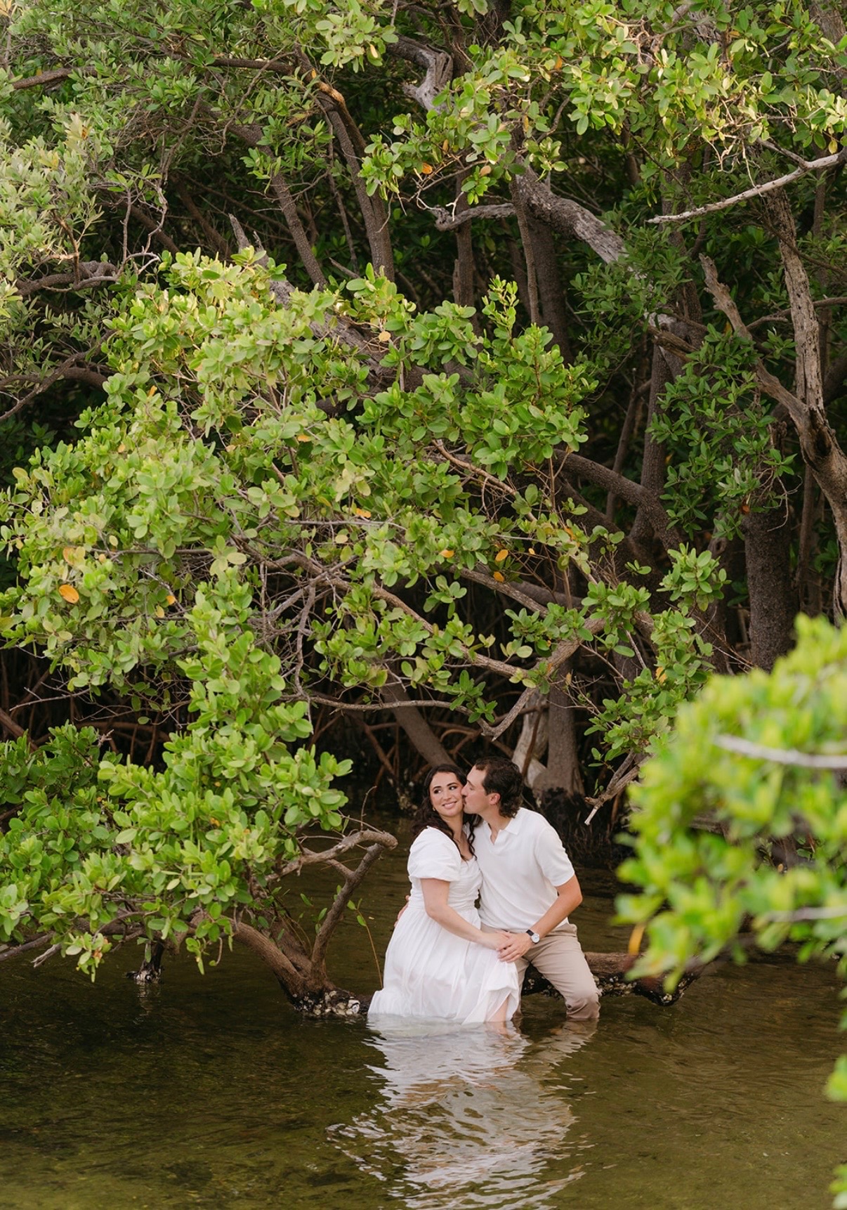 The couple seated in the water surrounded by green mangroves.